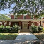 red brick, two-story house with wrap-around front porch.
