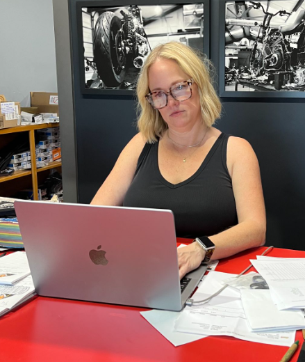 Amy sitting at a laptop with papers surrounding it.